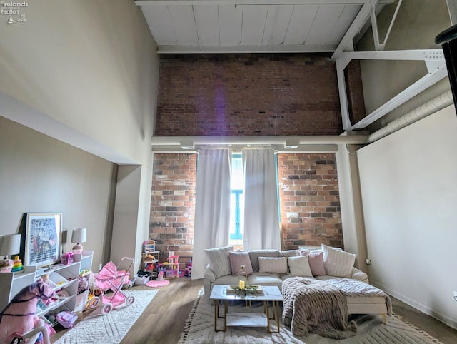 living room with wood-type flooring, brick wall, and a towering ceiling