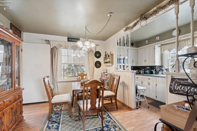 dining area with a healthy amount of sunlight, a chandelier, and light wood-type flooring