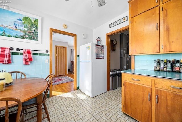 kitchen featuring white refrigerator and tile walls