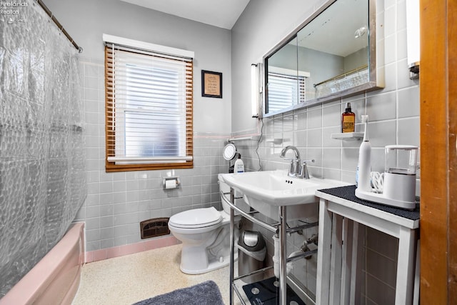 bathroom with bathing tub / shower combination, tile walls, and toilet