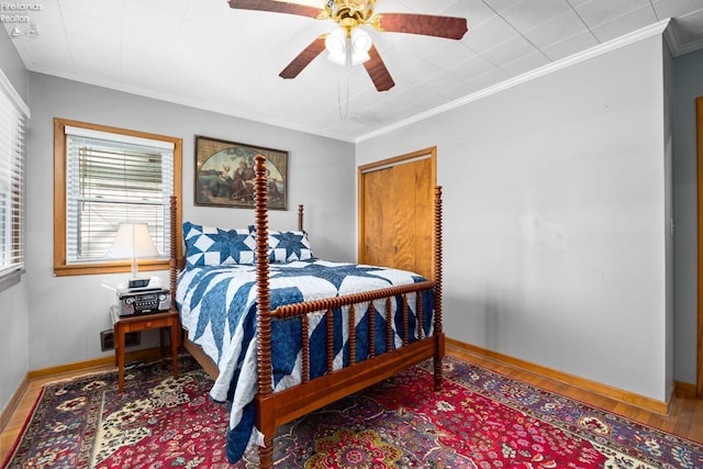 bedroom featuring hardwood / wood-style floors, ornamental molding, and ceiling fan