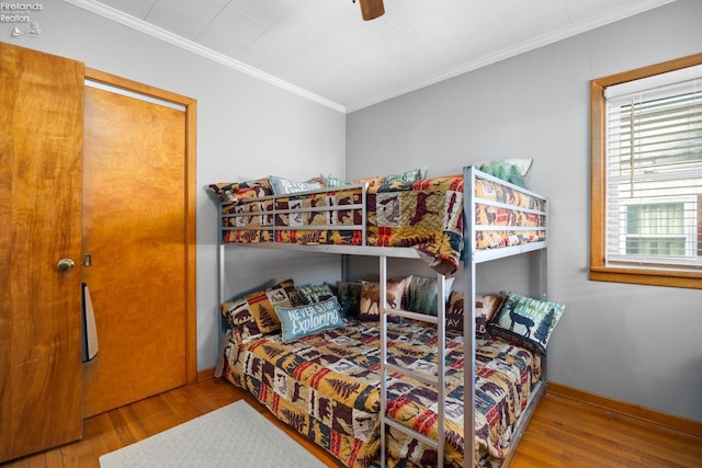 bedroom with multiple windows, hardwood / wood-style flooring, and ornamental molding