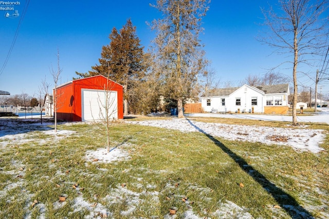 yard covered in snow with a garage and an outbuilding