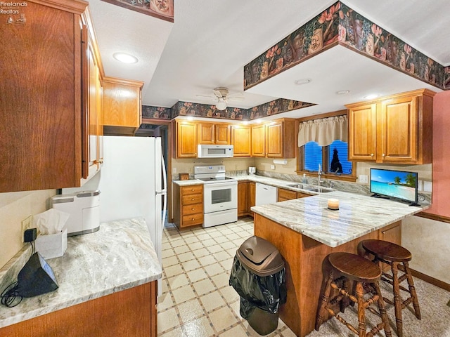 kitchen featuring sink, light stone counters, white appliances, kitchen peninsula, and ceiling fan