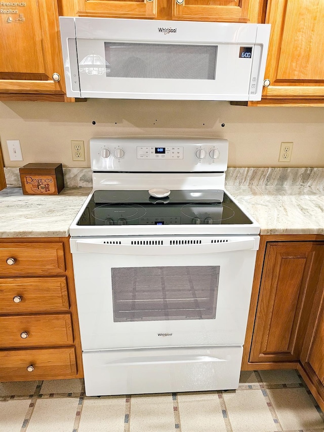 kitchen featuring white appliances and light stone countertops