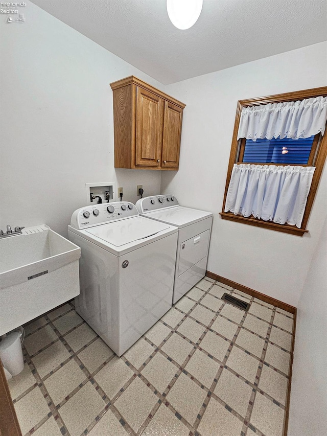 laundry room featuring cabinets, separate washer and dryer, sink, and a textured ceiling