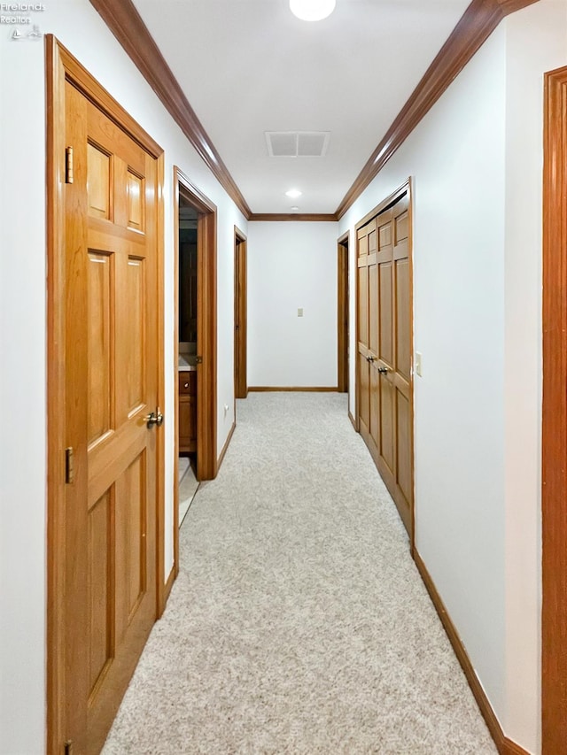 hallway featuring ornamental molding and light carpet