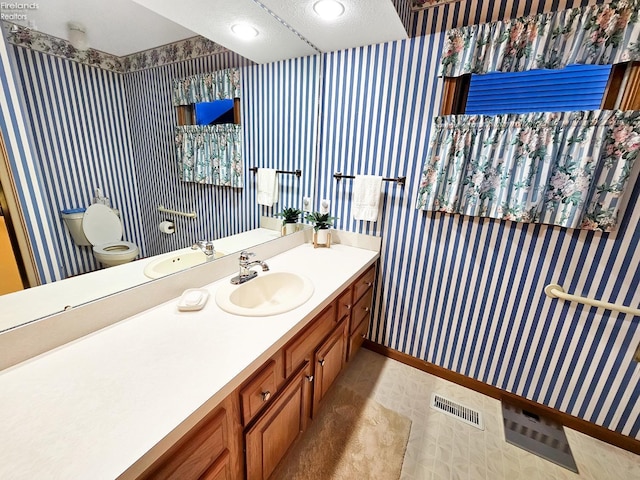 bathroom with vanity, a textured ceiling, and toilet