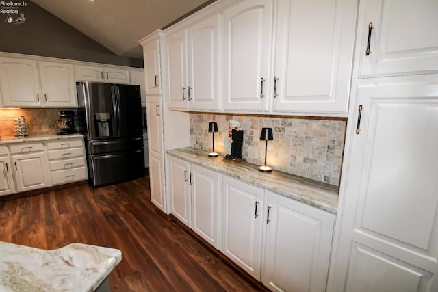 kitchen featuring lofted ceiling, white cabinetry, dark hardwood / wood-style floors, fridge with ice dispenser, and light stone counters