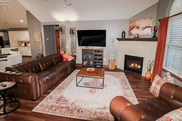 living room featuring ceiling fan, lofted ceiling, dark wood-type flooring, and a fireplace