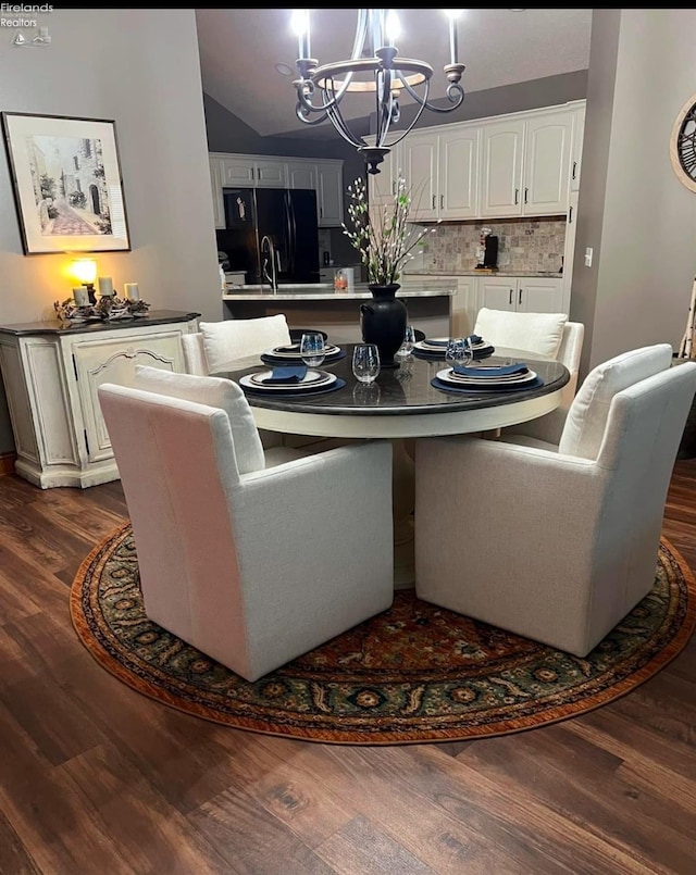 dining space with a notable chandelier, sink, and dark hardwood / wood-style floors