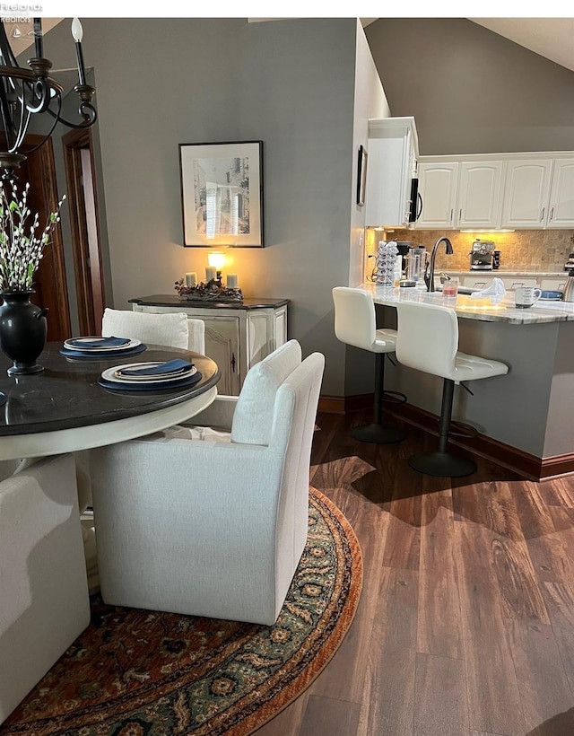 dining area featuring lofted ceiling, sink, and dark hardwood / wood-style floors