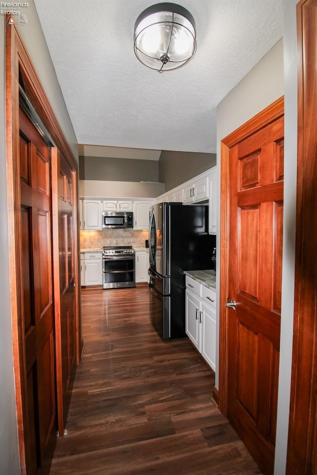 kitchen featuring dark wood-type flooring, appliances with stainless steel finishes, tasteful backsplash, a textured ceiling, and white cabinets