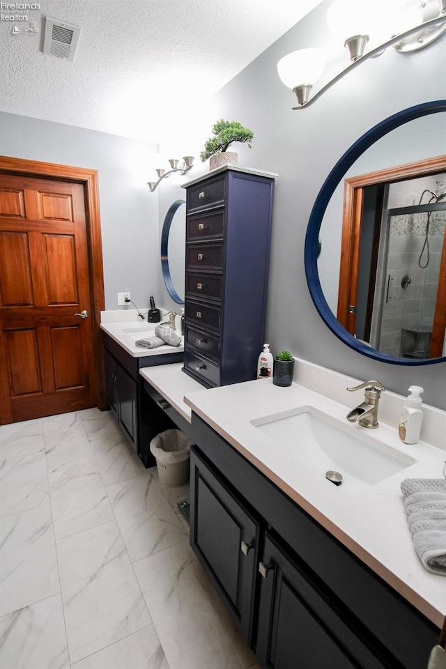 bathroom with a shower with door, vanity, and a textured ceiling