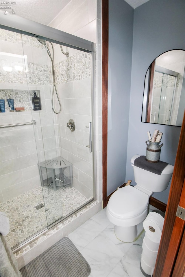 bathroom with a shower with shower door and toilet