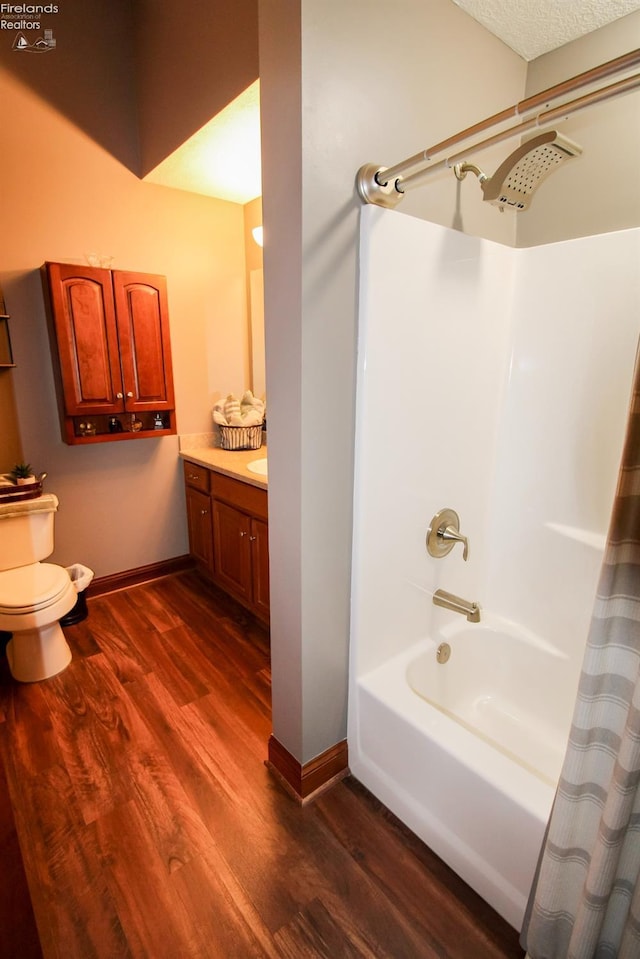 full bathroom with wood-type flooring, vanity, toilet, a textured ceiling, and shower / bath combo with shower curtain