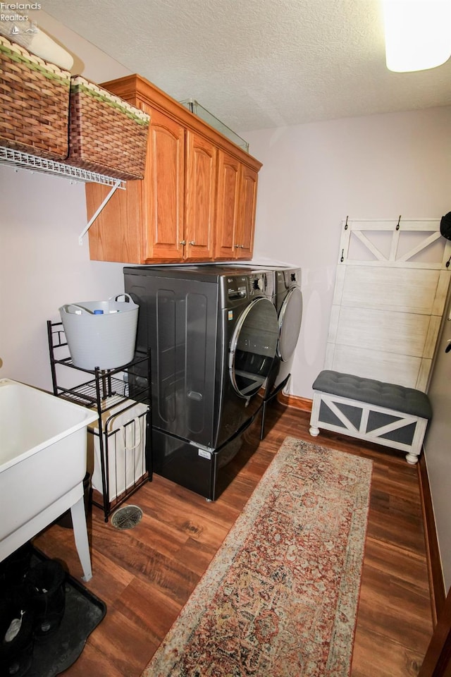 laundry room featuring dark wood-type flooring, cabinets, separate washer and dryer, and a textured ceiling