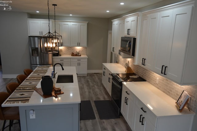 kitchen featuring white cabinetry, a center island with sink, stainless steel appliances, and a kitchen bar