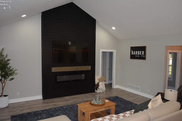 living room with lofted ceiling, a large fireplace, and dark hardwood / wood-style floors