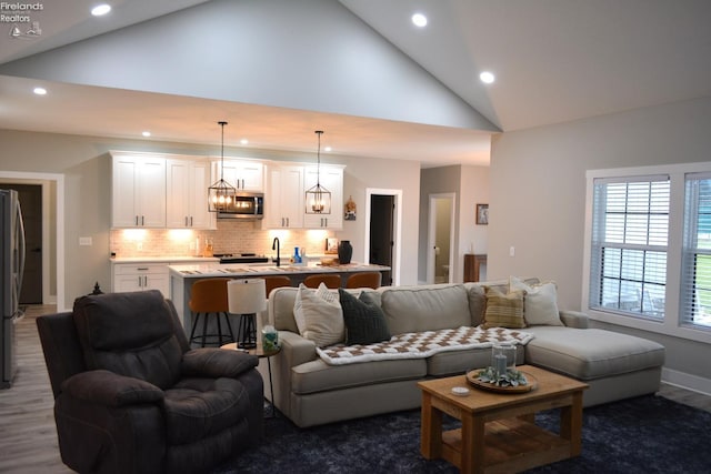 living room with an inviting chandelier, sink, dark wood-type flooring, and high vaulted ceiling