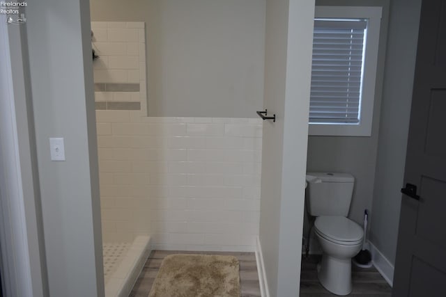 bathroom featuring tiled shower, hardwood / wood-style floors, and toilet