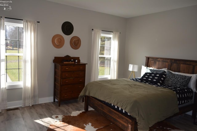 bedroom with multiple windows and light hardwood / wood-style flooring