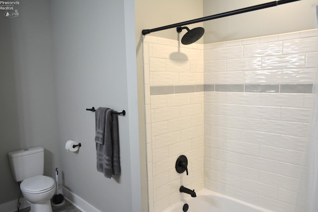 bathroom with tiled shower / bath combo and toilet