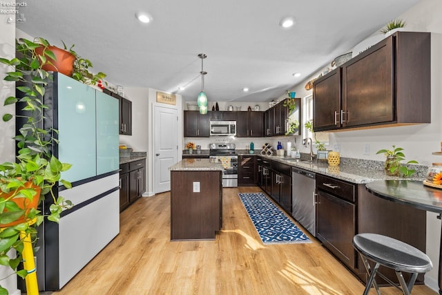 kitchen featuring dark brown cabinetry, a center island, appliances with stainless steel finishes, pendant lighting, and light hardwood / wood-style floors