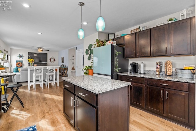 kitchen featuring light hardwood / wood-style flooring, hanging light fixtures, dark brown cabinets, and refrigerator