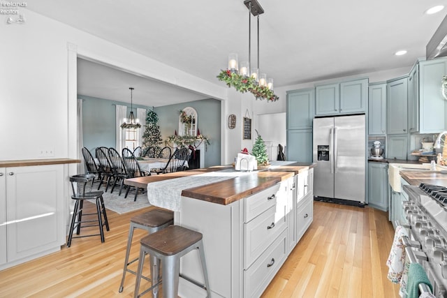 kitchen featuring stainless steel appliances, a breakfast bar area, butcher block countertops, and blue cabinets