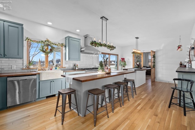 kitchen featuring a breakfast bar, sink, butcher block countertops, appliances with stainless steel finishes, and pendant lighting