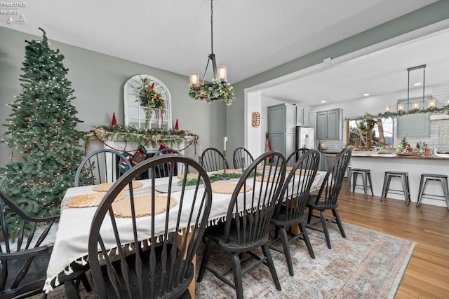 dining area with light hardwood / wood-style floors and a notable chandelier