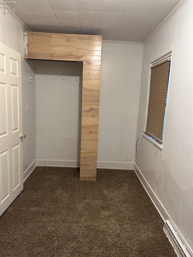 unfurnished bedroom with dark colored carpet, ornamental molding, and wooden walls