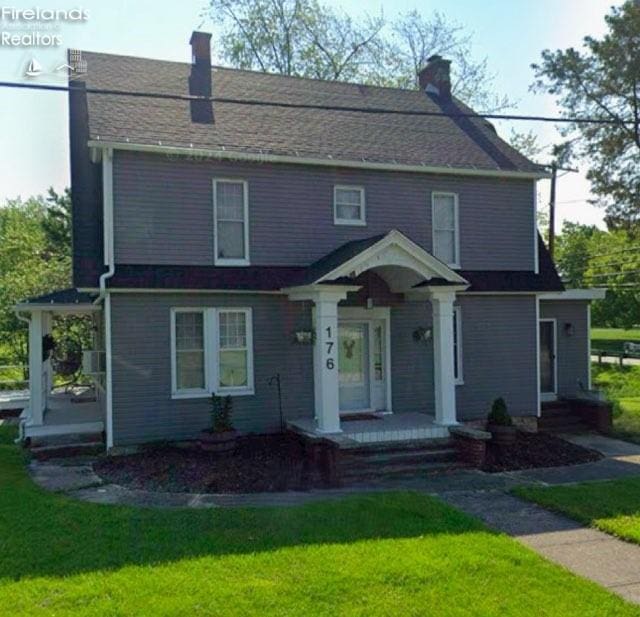 view of front facade with a chimney and a front yard