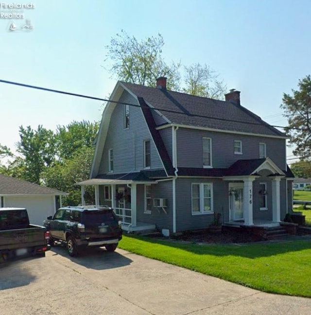 view of front of house with a front lawn, driveway, and a gambrel roof