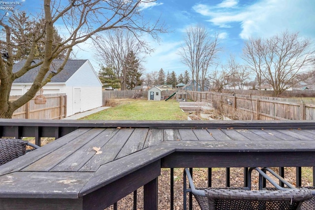 wooden deck with a storage shed, a yard, and a playground