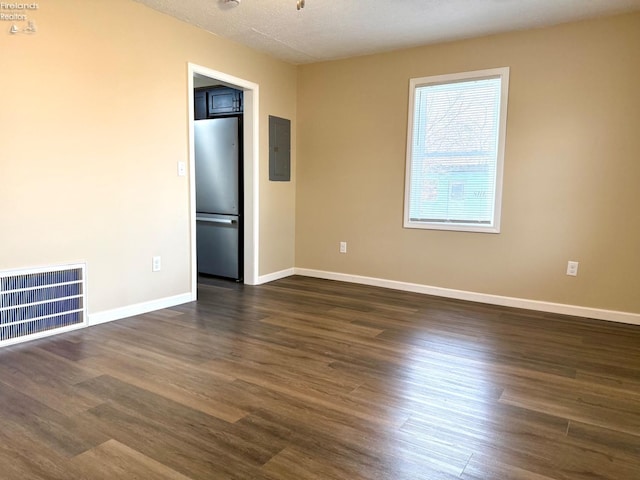 empty room with dark hardwood / wood-style flooring, electric panel, and a textured ceiling