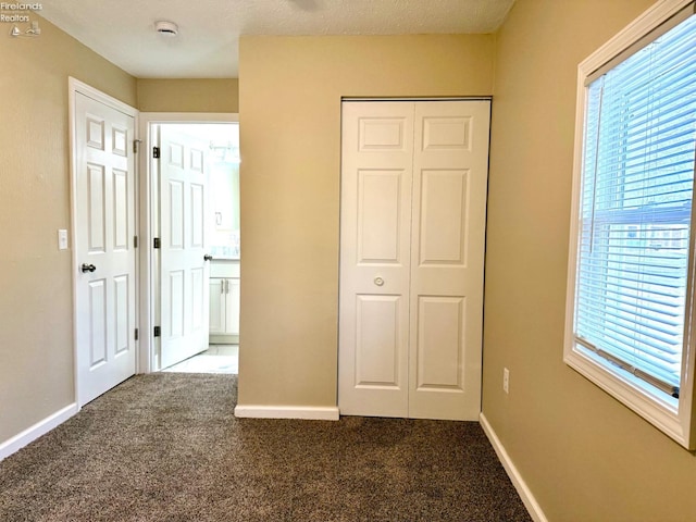 unfurnished bedroom with dark carpet and a closet