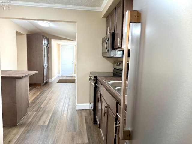 kitchen featuring stainless steel appliances, crown molding, hardwood / wood-style flooring, and sink