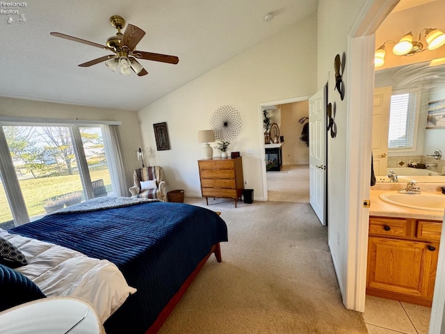 bedroom featuring multiple windows, vaulted ceiling, sink, and light carpet