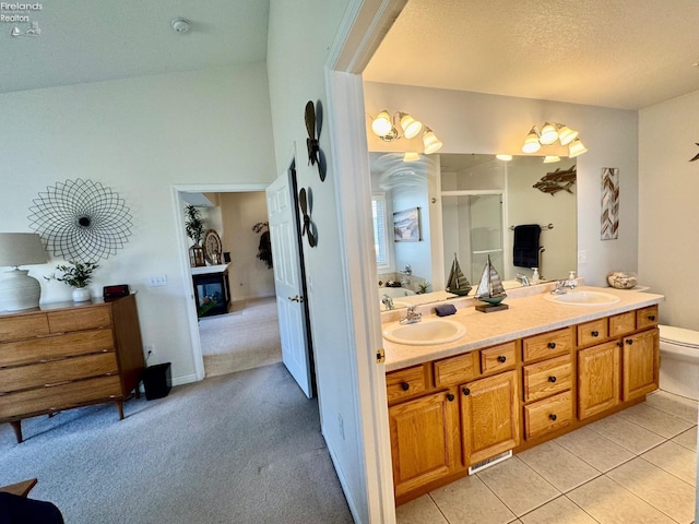 bathroom featuring tile patterned flooring, vanity, an enclosed shower, a textured ceiling, and toilet