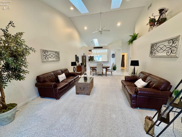 living room with ceiling fan, high vaulted ceiling, and a skylight