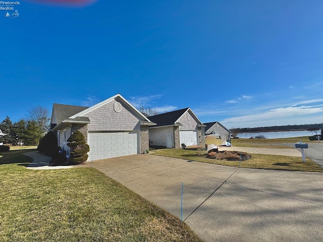 ranch-style house with a garage, a water view, and a front yard