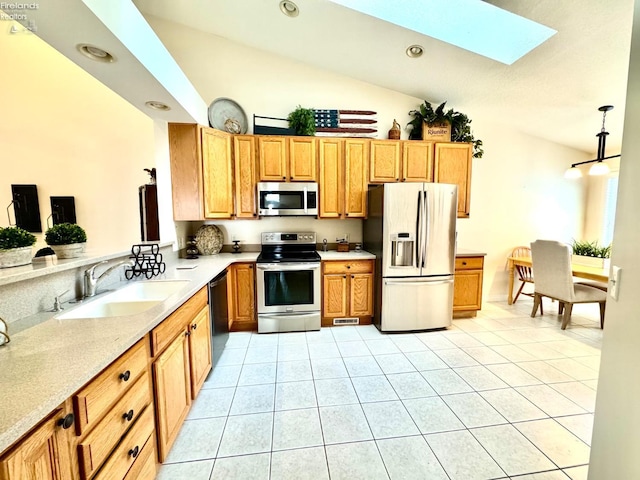 kitchen featuring appliances with stainless steel finishes, vaulted ceiling with skylight, sink, and light tile patterned floors