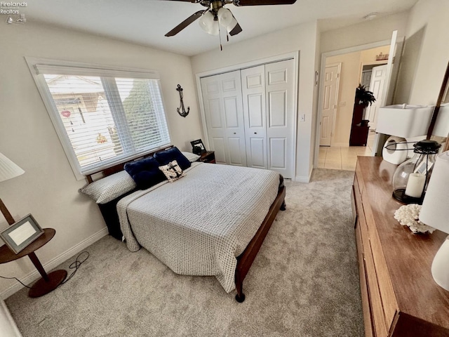 bedroom featuring light carpet, ceiling fan, and a closet