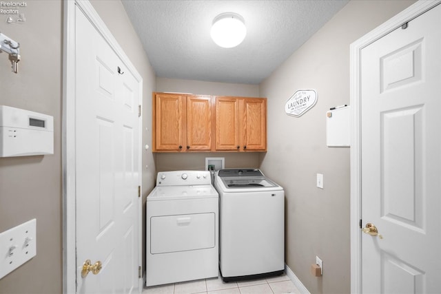 washroom featuring cabinets, light tile patterned floors, a textured ceiling, and washing machine and clothes dryer