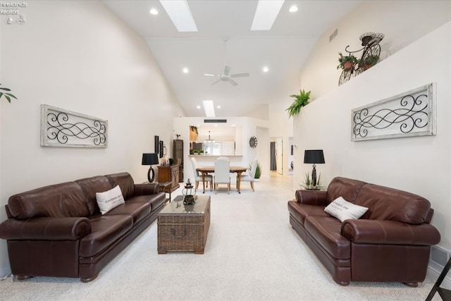 living room featuring ceiling fan, high vaulted ceiling, and a skylight