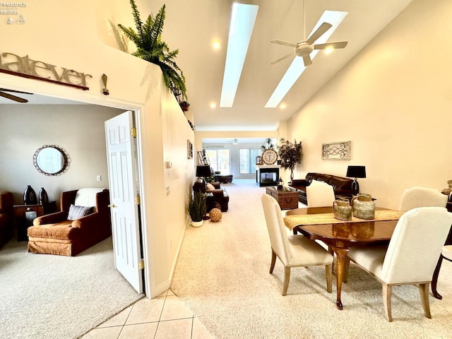 dining room with high vaulted ceiling, a skylight, light colored carpet, and ceiling fan