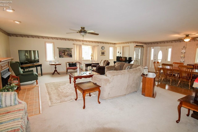 carpeted living room featuring a brick fireplace and ceiling fan