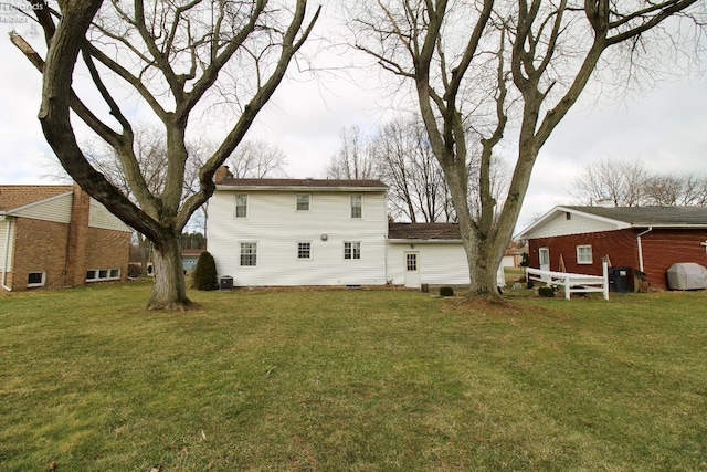 rear view of property featuring a yard and central air condition unit